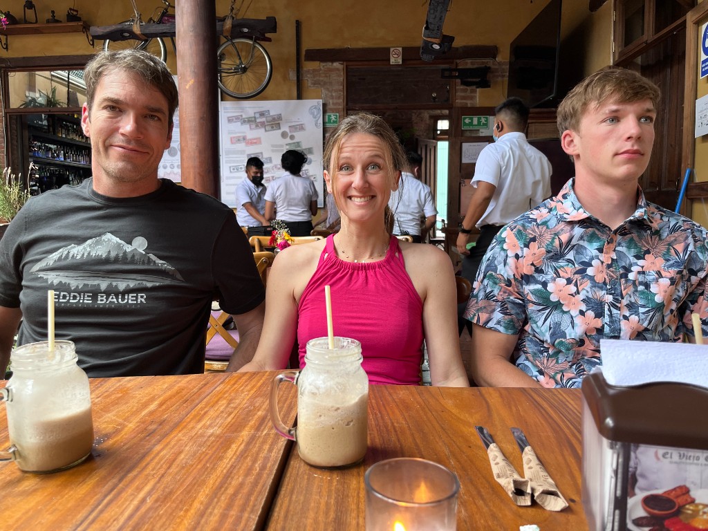Three family members at a rustic restaurant table with mason jar drinks